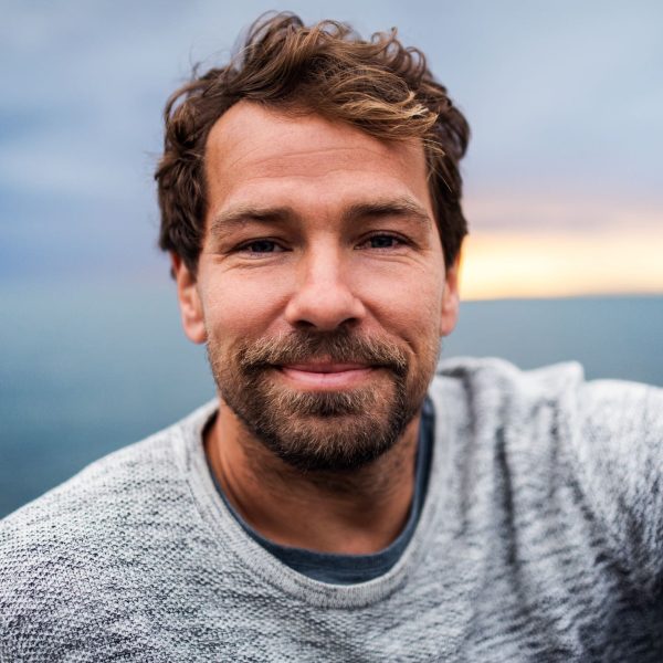 A portrait of happy handsome man standing outdoors, looking at camera.